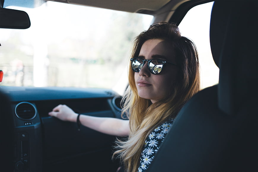Young woman with sunglasses sitting in car passenger seat