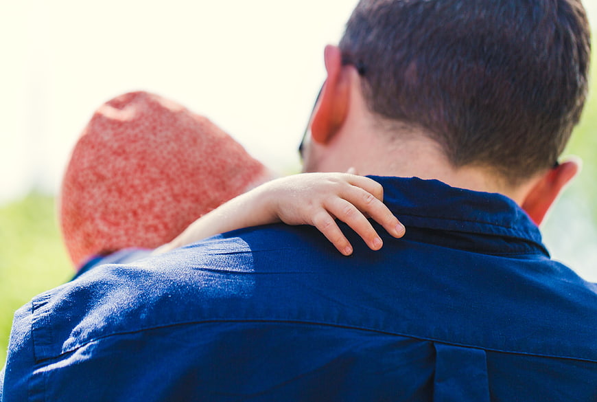 Father carrying child on shoulders outdoors