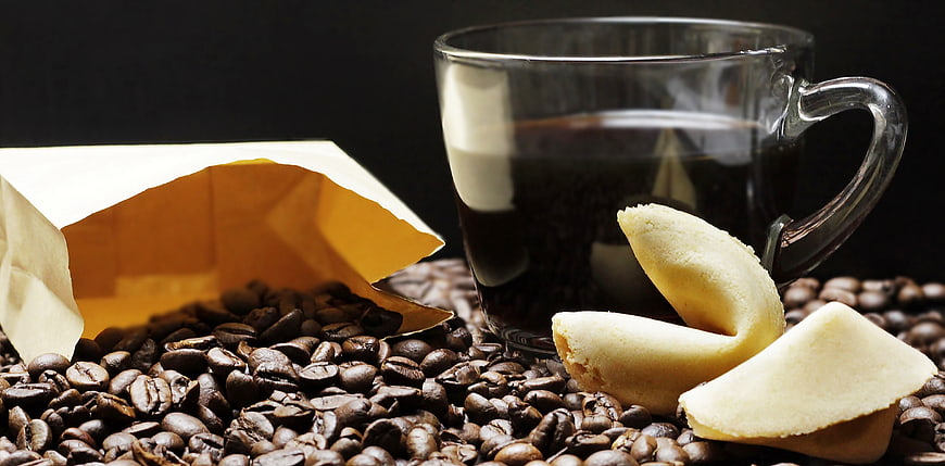 Coffee beans, black coffee in glass cup, and fortune cookies