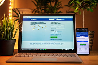 Facebook Registration Page on Laptop and Smartphone on Wooden Desk
