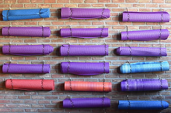 Colorful rolled yoga mats hanging on brick wall