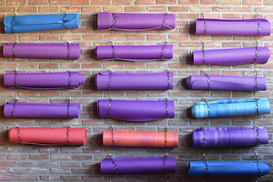 Colorful rolled yoga mats hanging on brick wall