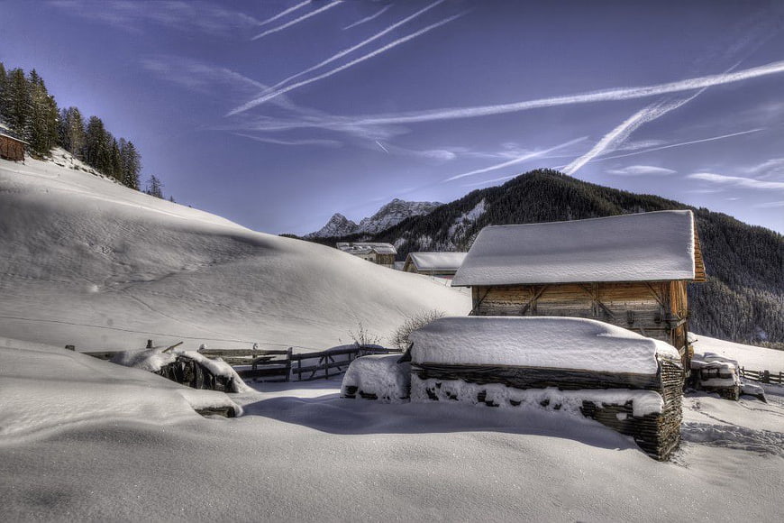 Snowy Alpine Cabin with Contrails in Blue Sky
