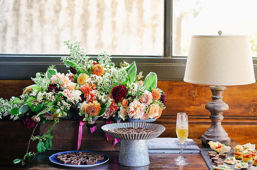 Rustic floral centerpiece with desserts and champagne on wooden table