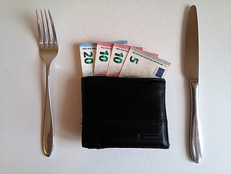 Black wallet with euro banknotes between fork and knife