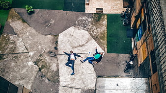 Aerial view of two men lying on urban pavement