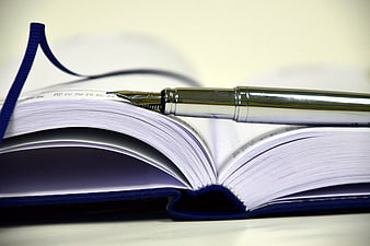Silver fountain pen on open blue notebook