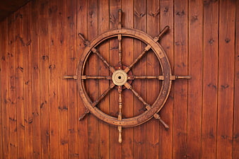 Vintage Wooden Ship Wheel Mounted On Rustic Vertical Plank Wall