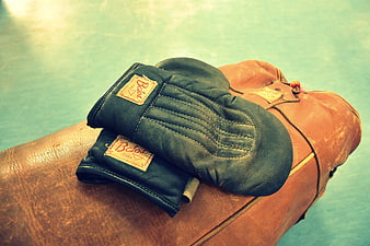 Vintage Blue Boxing Gloves on Worn Leather Punching Bag
