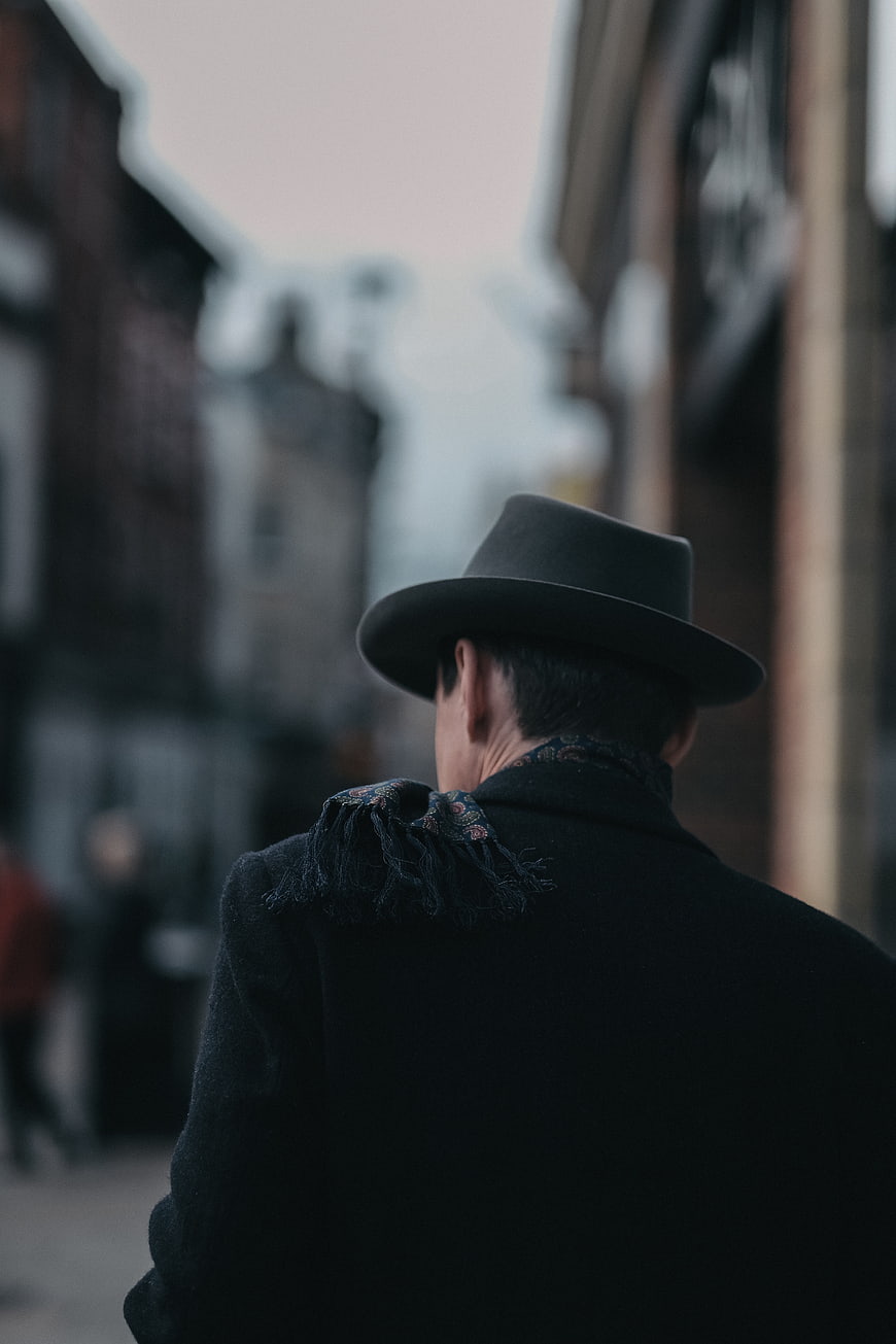 Man in Fedora Hat Walking Down City Street