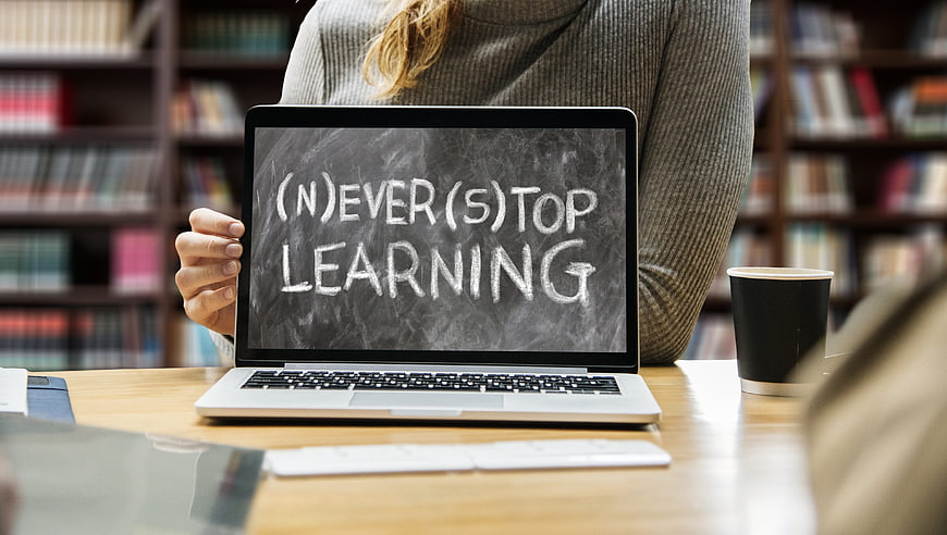 Woman holding laptop with never stop learning text in library