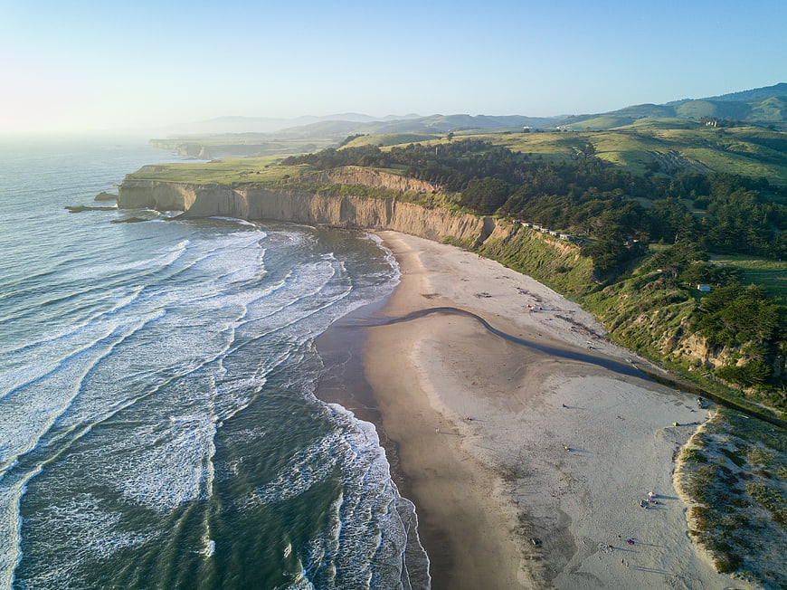 Aerial View of Scenic Coastal Beach with Cliffs and Rolling Hills