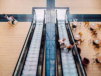 Top-down view of shoppers on escalators in a modern shopping mall atrium