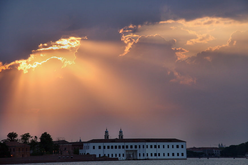 Dramatic sunset sunbeams over white building in Venice