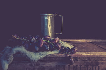 Vintage still life with grapes and metal pitcher on wood