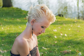 Profile of young blonde woman looking down in park