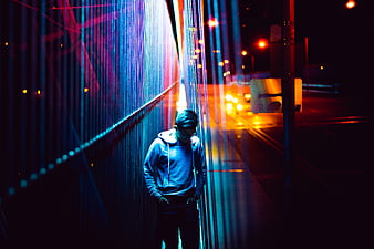 Man walking alone at night with neon light streaks