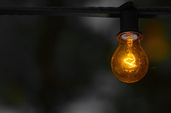 Glowing Vintage Light Bulb Hanging on Dark Background