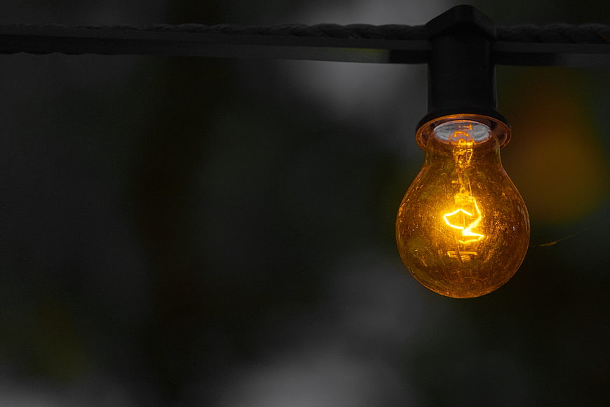 Glowing Vintage Light Bulb Hanging on Dark Background