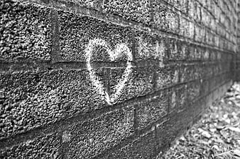White chalk heart symbol drawn on a textured gray brick wall