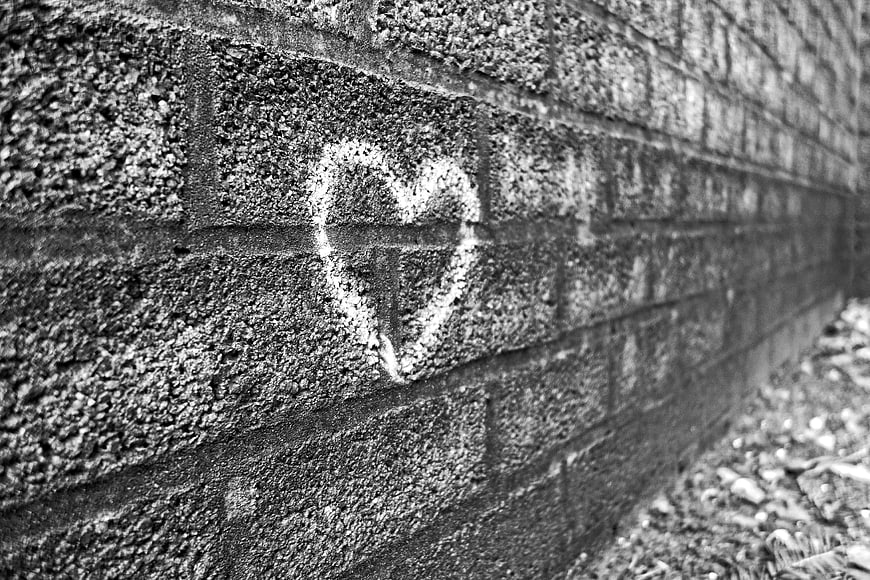 White chalk heart symbol drawn on a textured gray brick wall