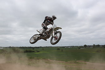 Motocross Rider Mid-Air Jump Over Green Countryside