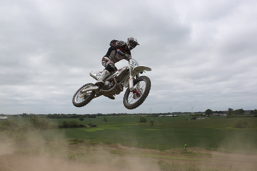 Motocross Rider Mid-Air Jump Over Green Countryside