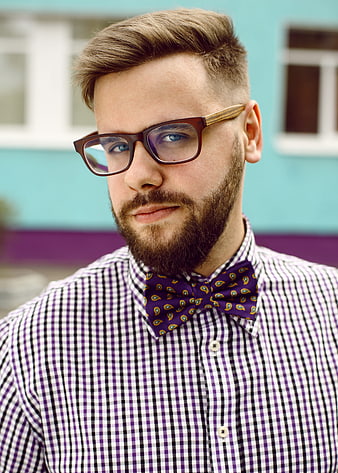 Portrait of a bearded man wearing glasses and a purple paisley bow tie