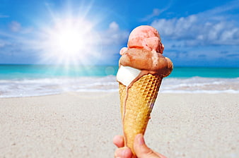 Triple scoop ice cream cone held on a sunny tropical beach