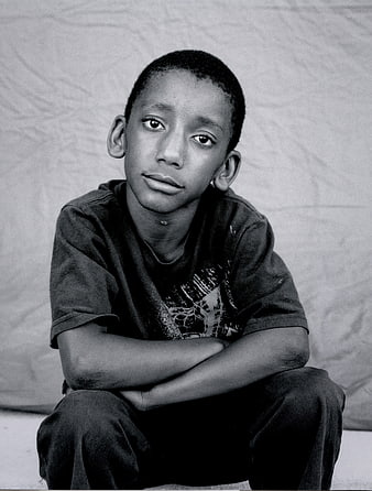 Black and white portrait of a young boy sitting alone