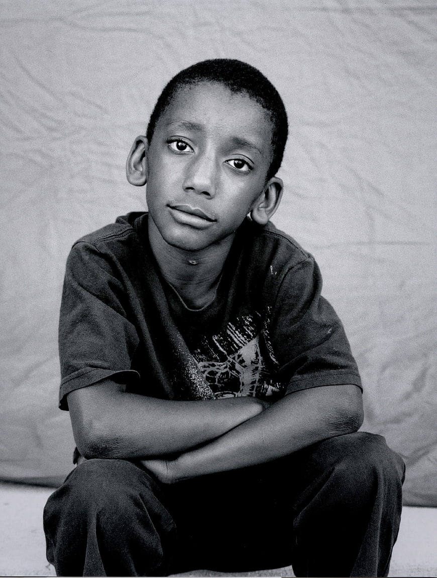 Black and white portrait of a young boy sitting alone