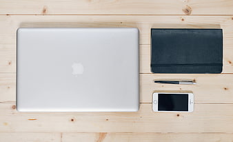 Flat lay of silver laptop, notebook, pen, and smartphone on wood