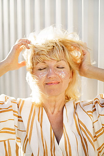 Senior woman with glitter on face and messy blonde hair
