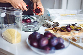 Hands slicing fresh plums for baking preparation