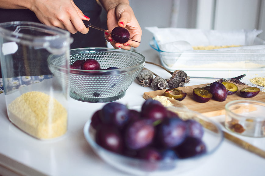 Hands slicing fresh plums for baking preparation