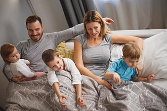 Happy family relaxing together in bed with children