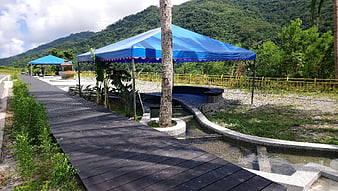 Wooden walkway leading to blue canopy spa area with mountain backdrop