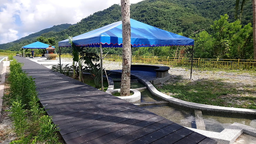 Wooden walkway leading to blue canopy spa area with mountain backdrop