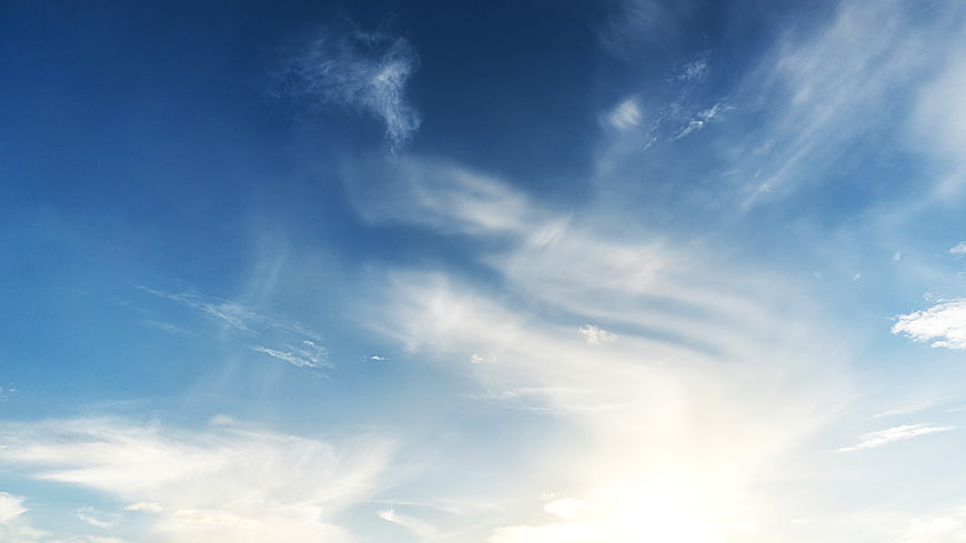 Bright blue sky with wispy white clouds and sunlight