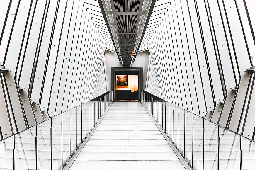 Modern white architectural corridor with glass railings and geometric lines