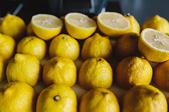 Fresh yellow lemons with cut halves on a surface