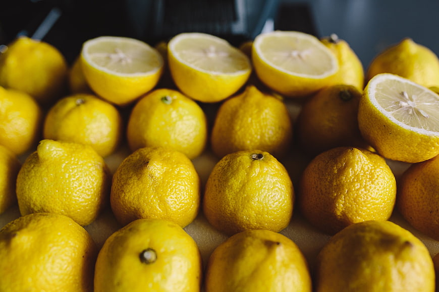 Fresh yellow lemons with cut halves on a surface