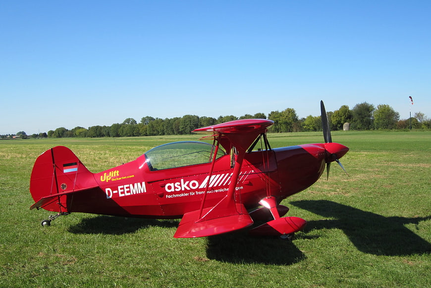 Red biplane parked on grassy airfield