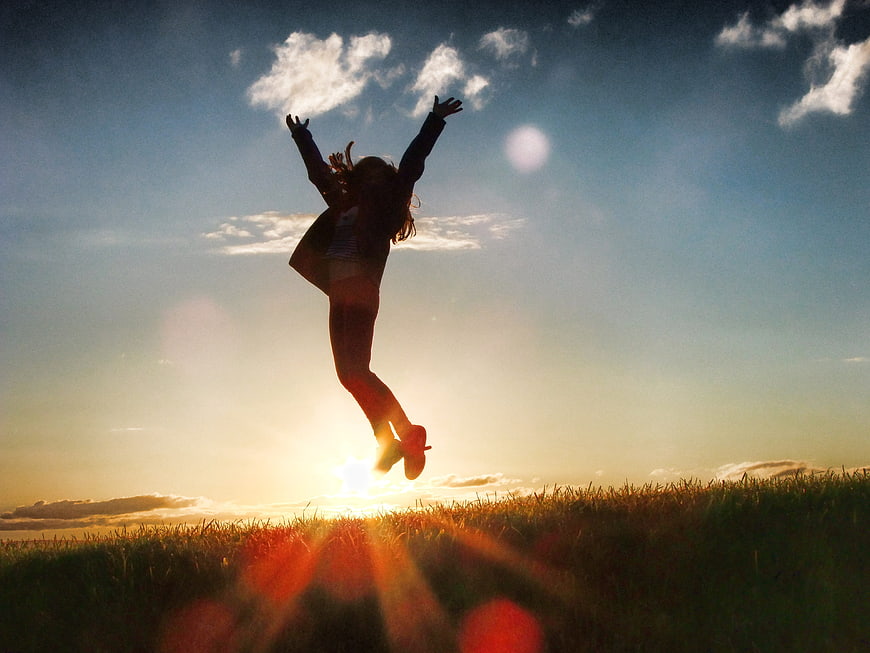 Silhouette of Woman Jumping in Field at Sunset
