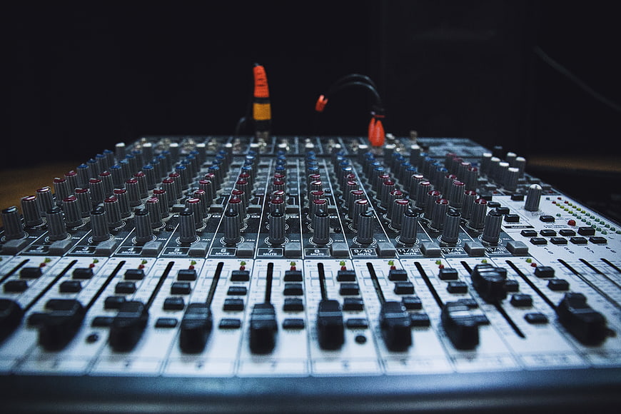Close-up of professional audio mixing console with sliders and knobs
