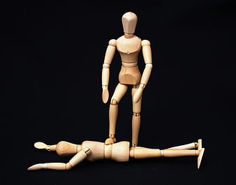 Wooden mannequins depicting dominance and defeat on black background
