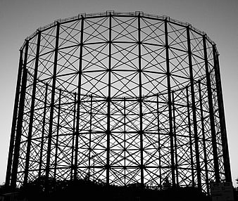 Black and white silhouette of a large gas holder structure