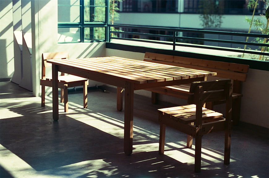 Sunlit wooden table and chairs on a modern balcony