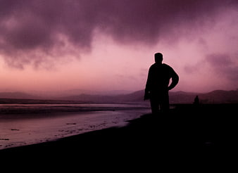 Silhouette of Man Standing on Beach at Purple Sunset