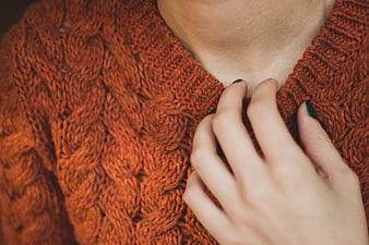 Close-up of woman's hand on rust-colored cable knit sweater